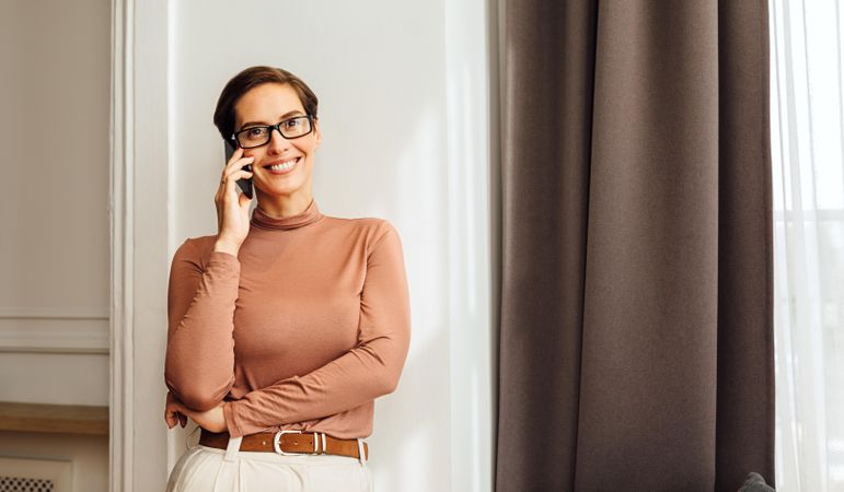 Woman in smart casual outfit smiling while on a cell phone