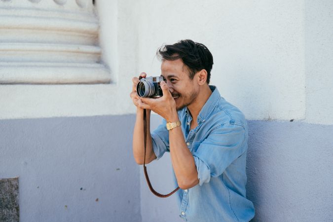 Man with beard taking a photo holding the camera up to his eye