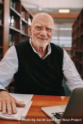 Smiling older man sitting in library with college materials 439Xg0