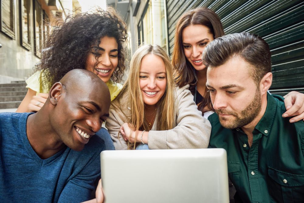 Male and female friends watching something on digital tablet while sitting on outdoor stairs