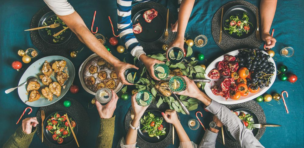 Group toasting at festive table with candy canes and roasted pears, wide composition