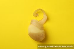 Partially peeled potato on yellow background 4dvDn0