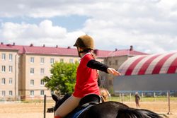 Young rider practices posture during outdoor equestrian training session.