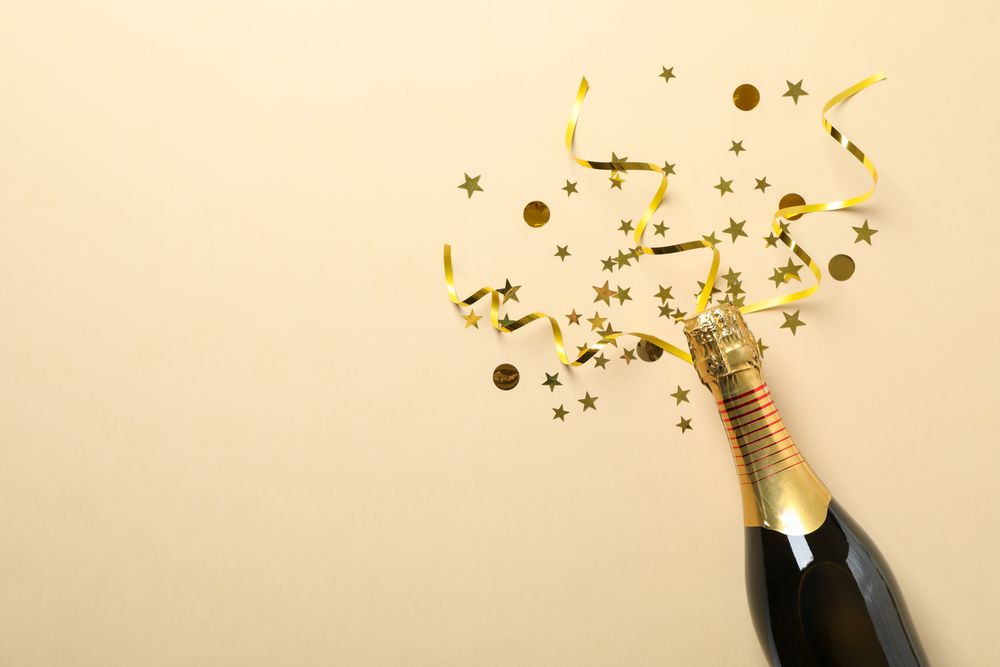 Champagne bottle and glitter on beige background, space for text