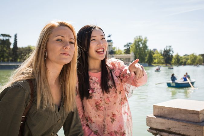 Cheerful multiracial friends sitting on embankment