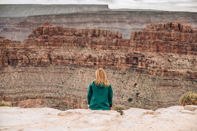 Female relaxing on cliff and admiring picturesque view