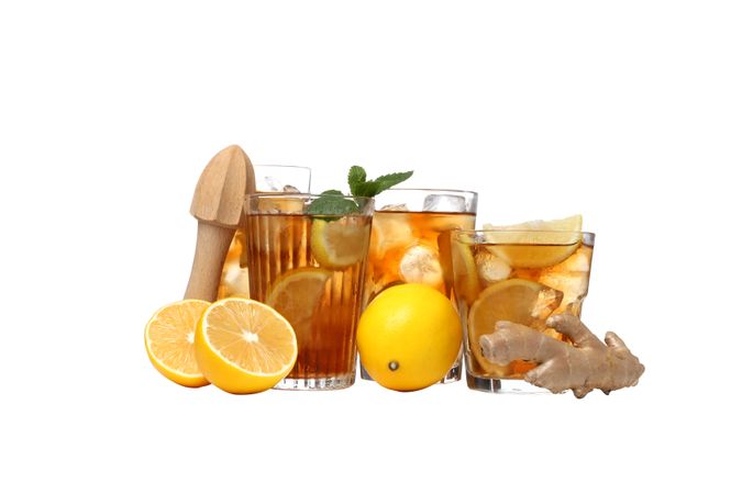 Glasses of cold tea with orange and ginger, isolated on plain background