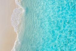 Overhead shot of beautiful clear blue water coming up on a beach