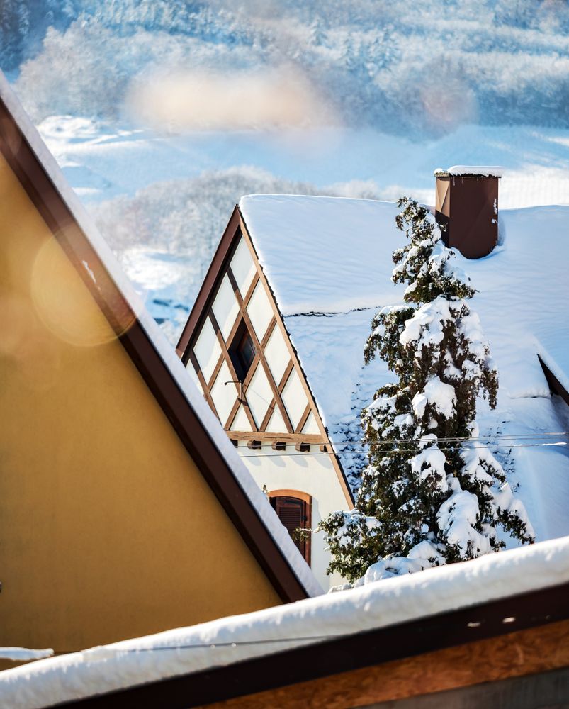 Sunny winter day. Snow-covered roofs of houses. Village in Alsace.
