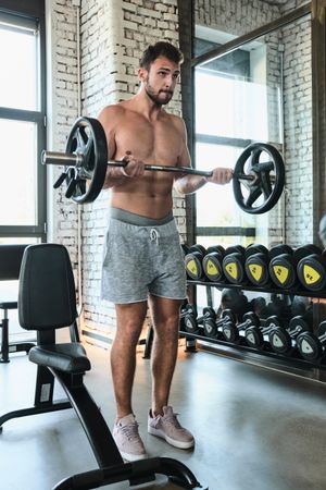 Bearded man exercising with barbell in gym