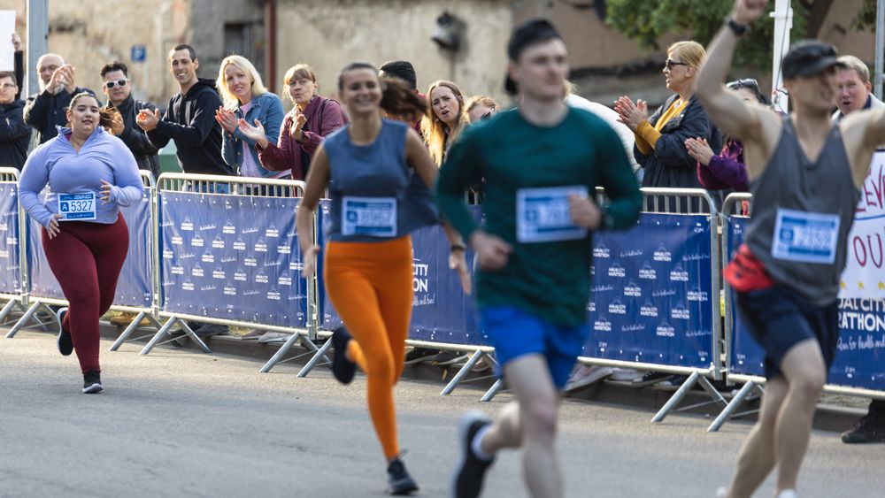Diverse Group of People Running a Marathon in a City During the Day.