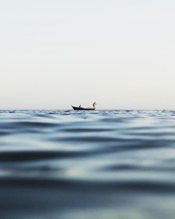 Person standing on small boat in the middle of the sea