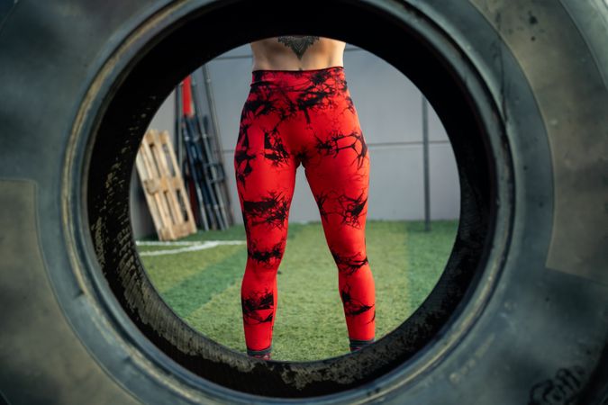 Woman's red leggings seen through inside of tire
