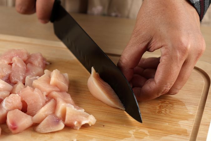 Woman Cutting the Chicken Fillet in Pieces for Cooking.