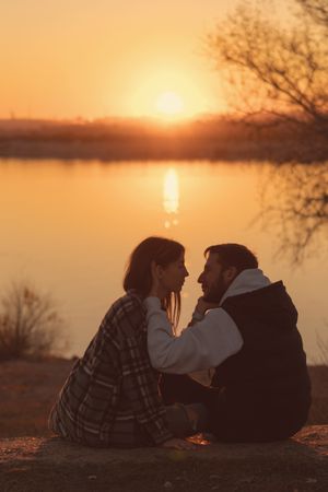 Couple sitting sunset lake