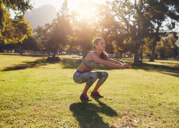 Woman doing exercise squats outside at a park