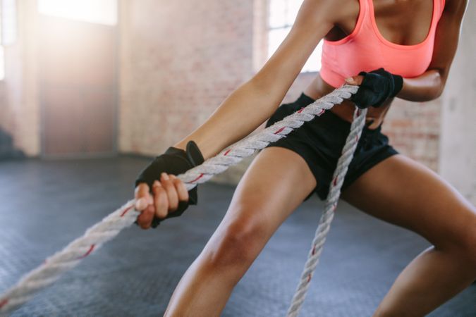 Cropped shot of strong young woman pulling rope at a gym