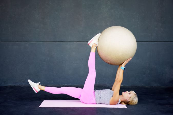 Fit woman doing mat workout with stability ball