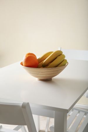 Bowl with oranges and bananas on table