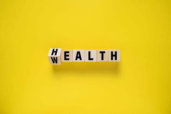 flip wooden blocks with wealth and health words isolated on yellow background