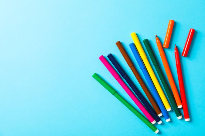 Flat lay composition with multicolor markers on blue background, space for text