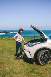 Woman looking engine of broken down car