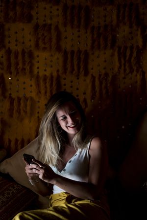 Smiling woman using smartphone in dark room