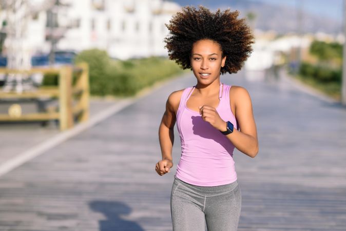 Black woman, afro hairstyle, running outdoors in city road