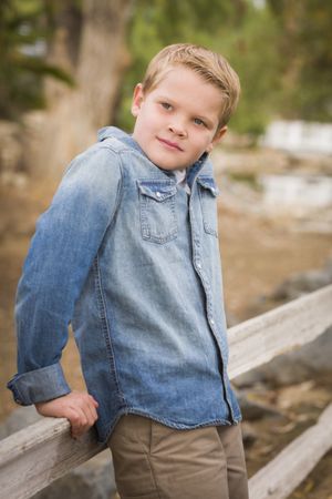 Handsome Young Boy Against Fence in Park