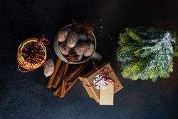 Top view of Christmas items, walnuts, orange slices, cinnamon sticks, present and mini tree