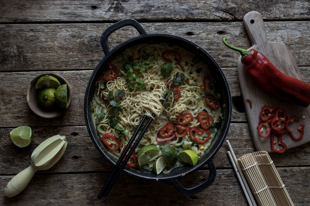 Green curry noodles in pot on table
