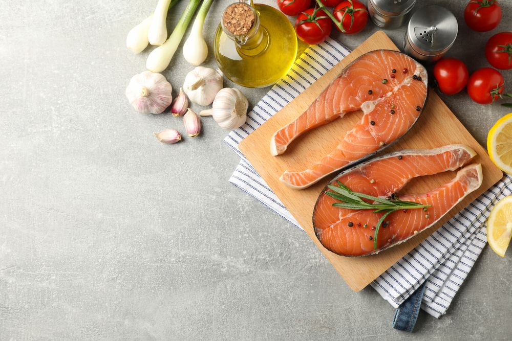 Composition with salmon meat and ingredients on gray background, top view
