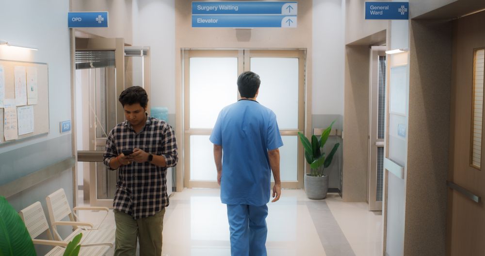 Backview Shot of Young Male Doctor Walking in Hospital Corridor.