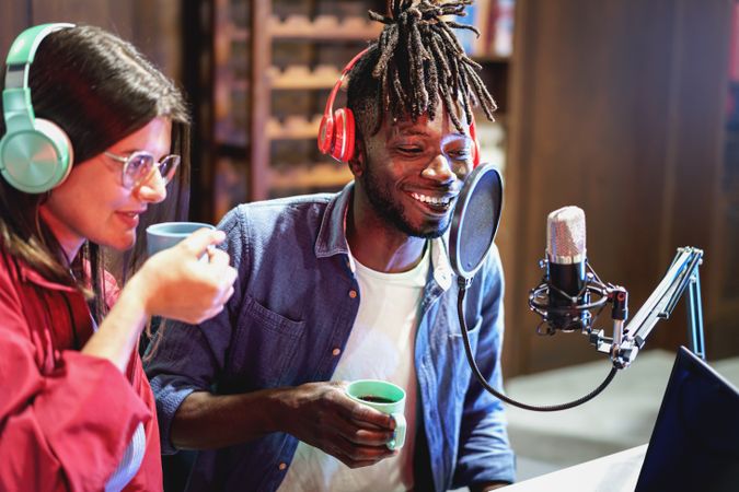 Multi-ethnic young people recording podcast using microphones with anti-pop filter