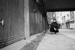 Woman outside crouching down smiling in hijab