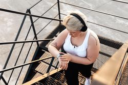 Curvy blond woman checking smart watch walking up staircase