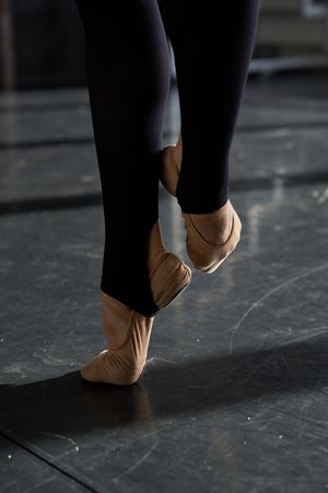 Feet of a professional ballet dancer in a warm-up before rehearsal