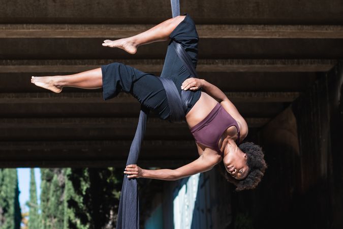 Slim woman doing aerial yoga in city