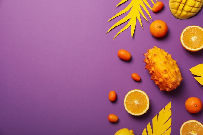 Tropical fruit and paper leaves on purple background, space for text