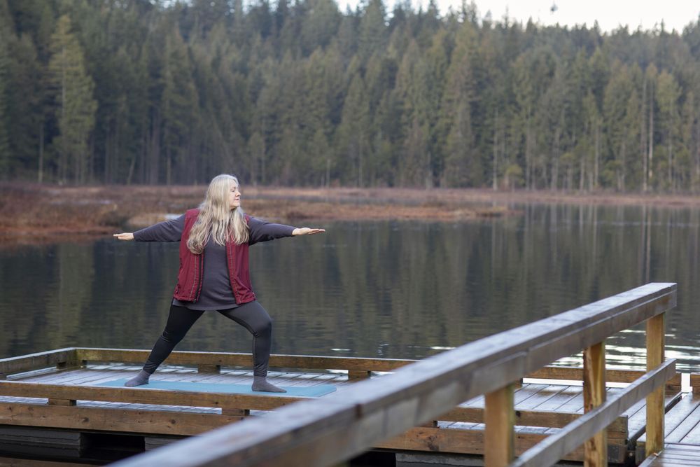 Woman doing yoga on a lake dock