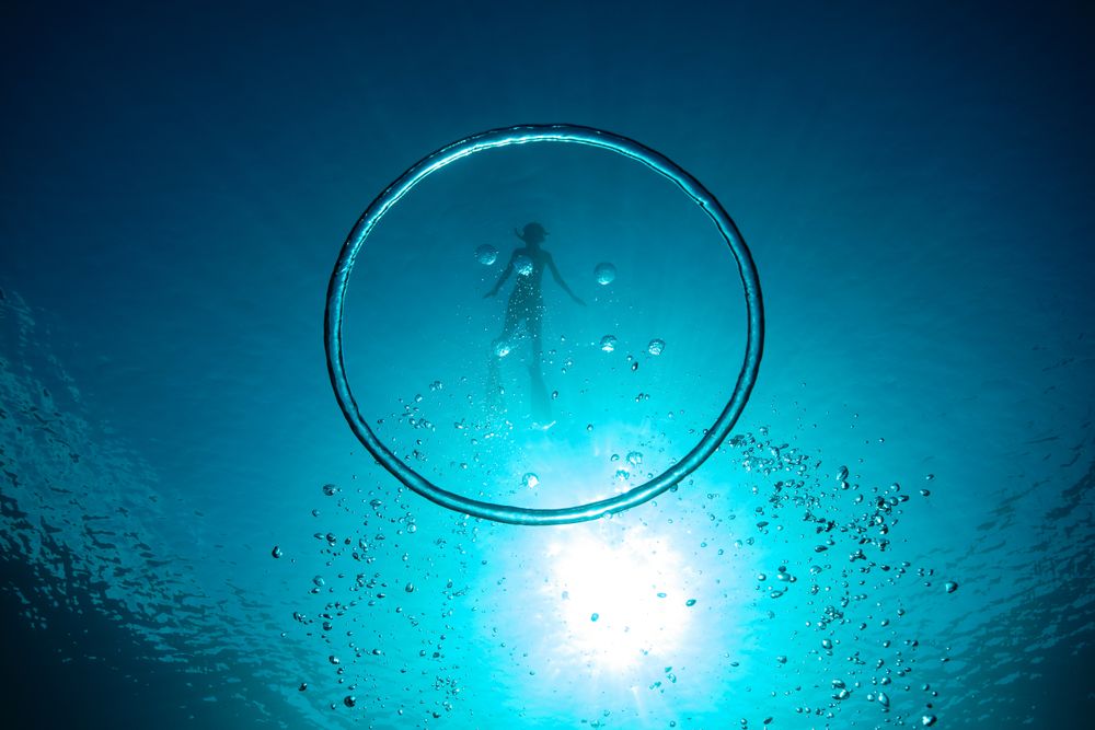 Bubble ring with diver swimming in blue water
