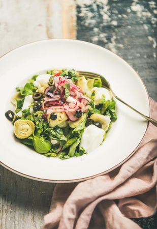 Artichoke salad in bowl, on blue painted wooden background with linen napkin