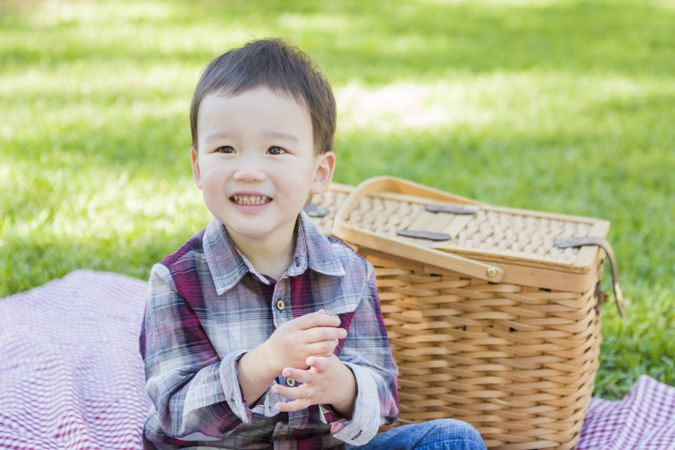 Young Boy Sitting in Park Near Picnic Basket