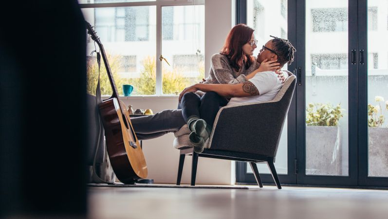 Passionate couple relaxing on armchair in living room