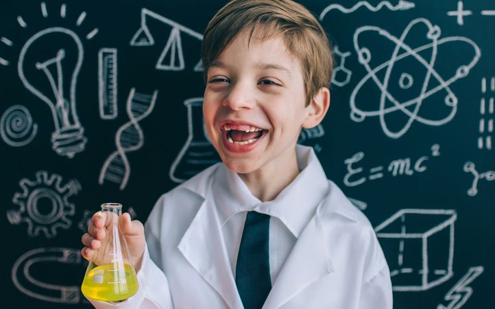 Happy kid laughing and showing yellow liquid in flask