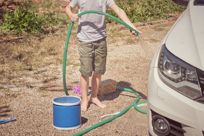 Boy washing car on sunny day