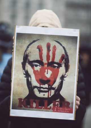 London, England, United Kingdom - March 5 2022: Person holding sign of Putin’s face with red hand