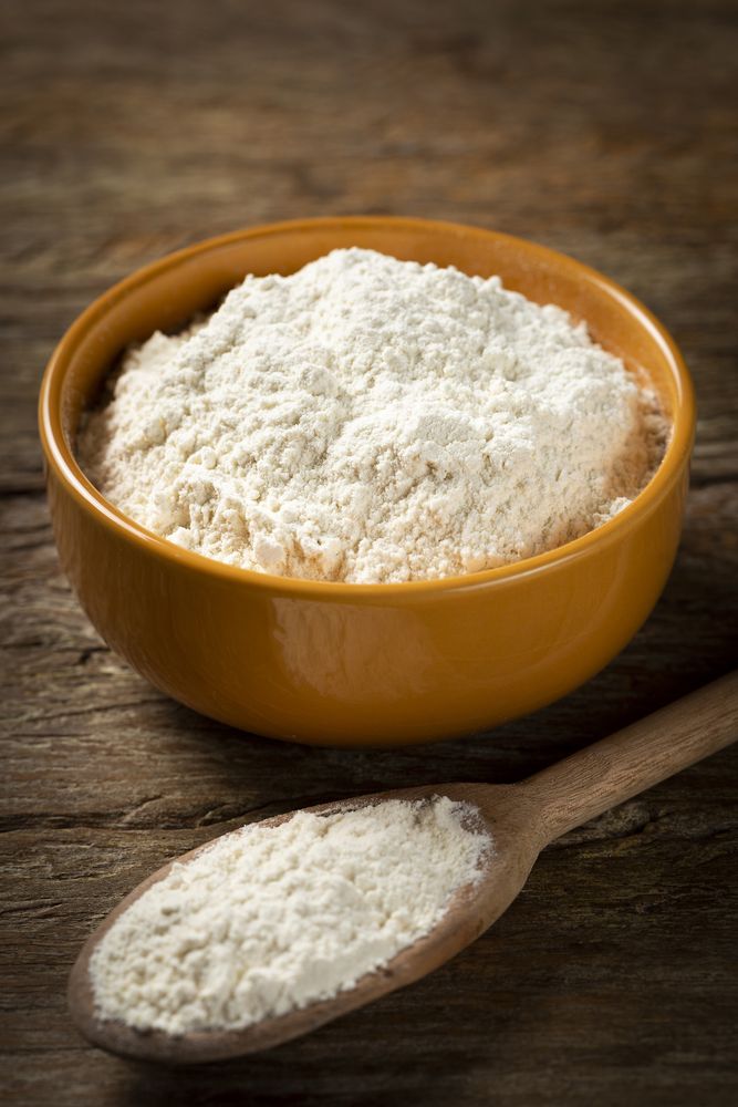 Bowl with wheat flour on the table.