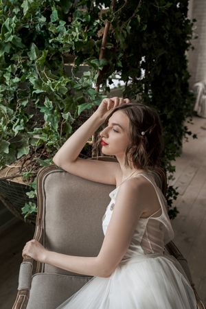 dreamy woman with red lips in white dress sitting on armchair