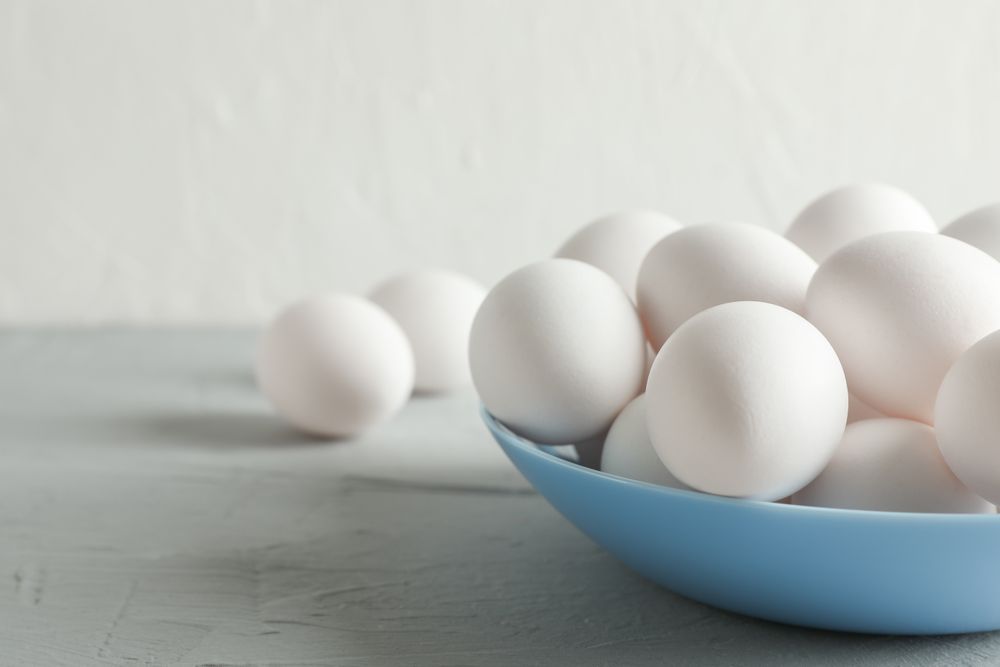 chicken eggs in plate on grey table against light background, space for text